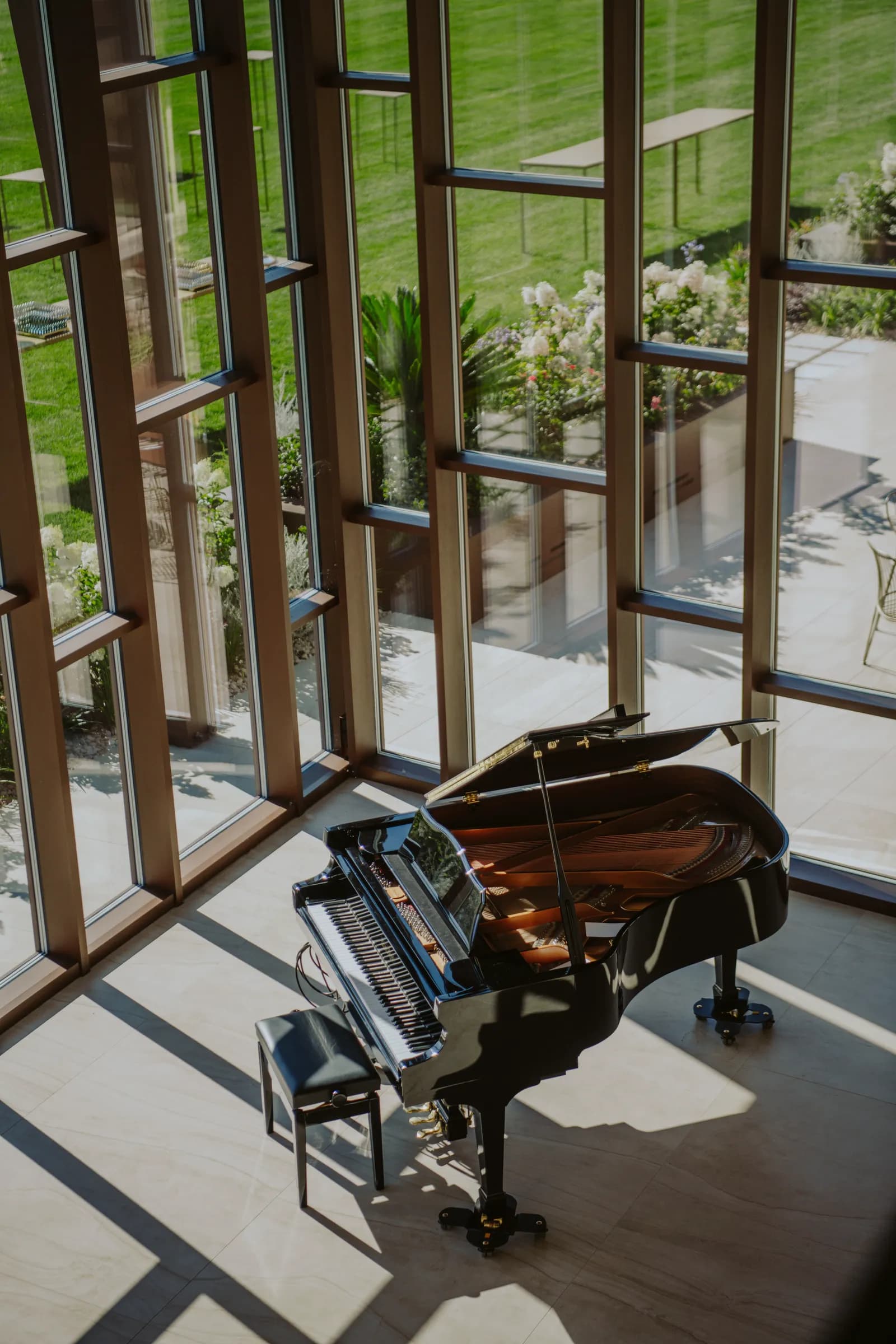 Il pianoforte a coda accanto alle grandi vetrate, con il prato oltre il vetro