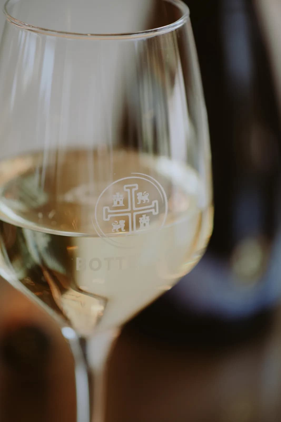 Ein Glas Schaumwein mit dem Wappen des Weinguts