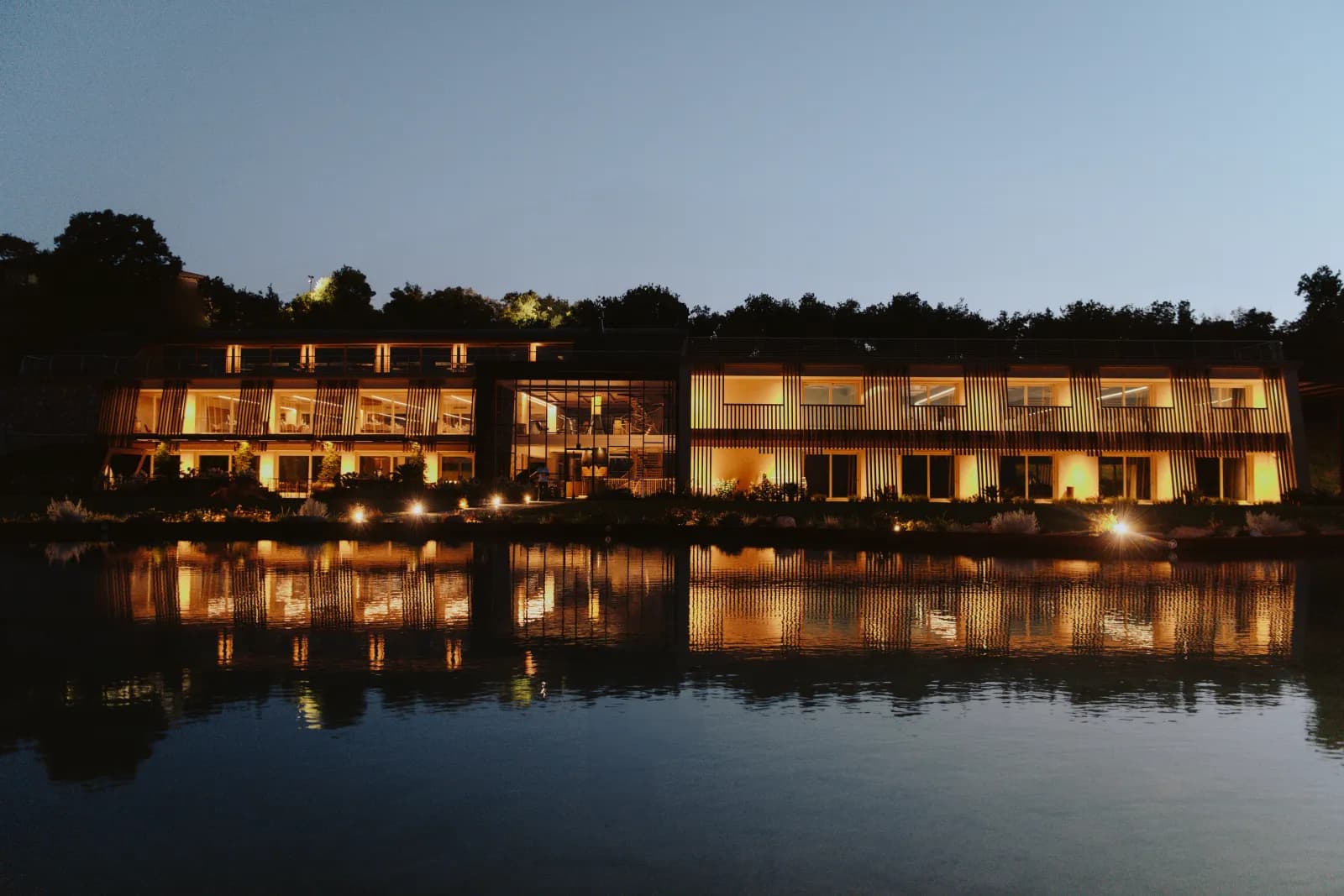 Das beleuchtete Weingut bei Nacht, im Teich gespiegelt