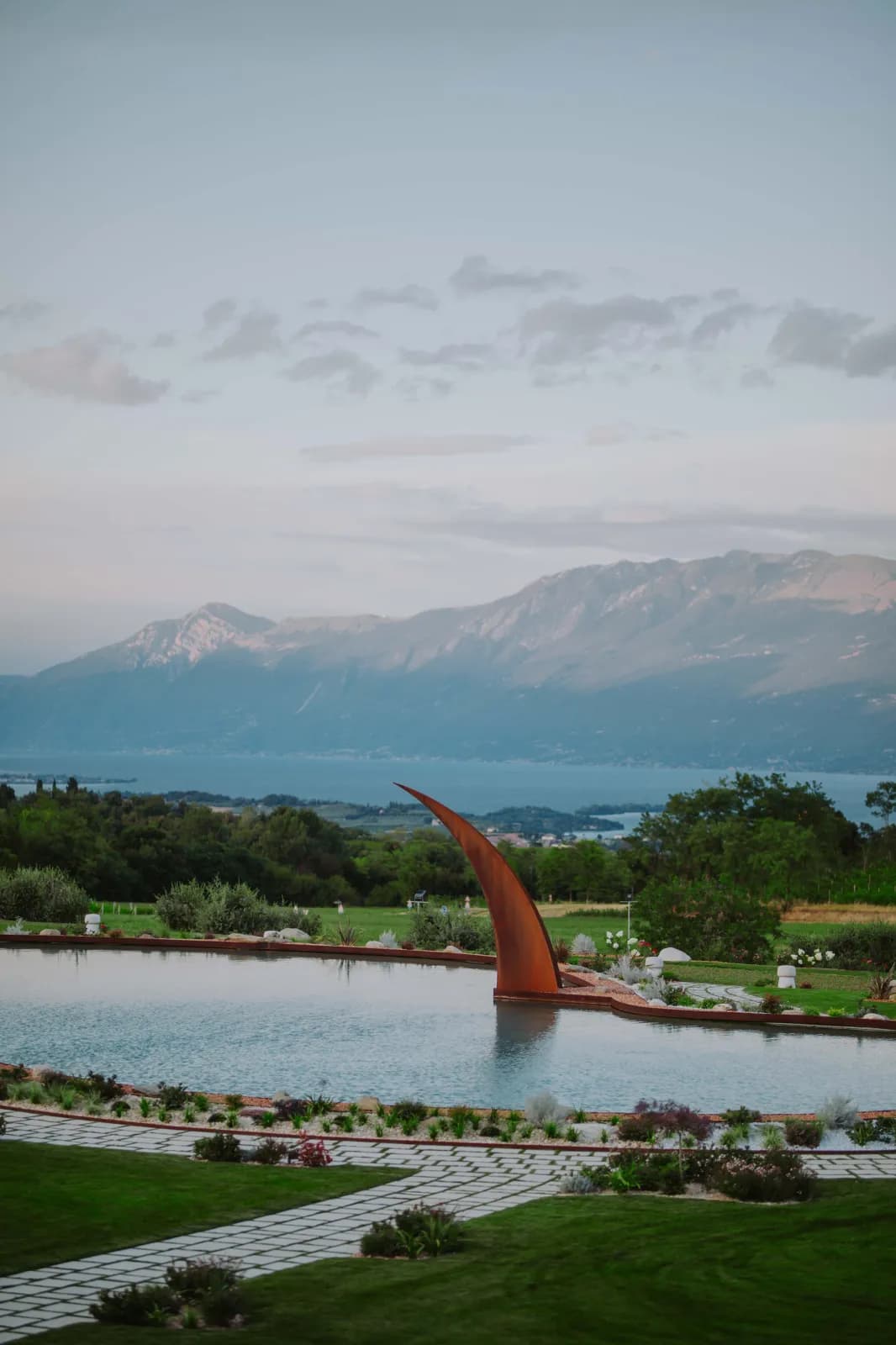 Die Skulptur am Teich bei Sonnenuntergang, mit dem Gardasee