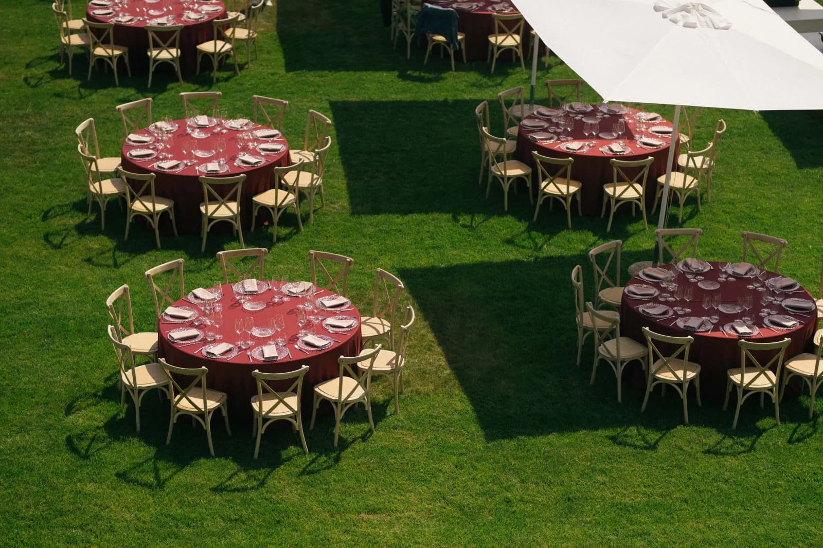 Tische mit roten Tischdecken auf der Wiese, von oben