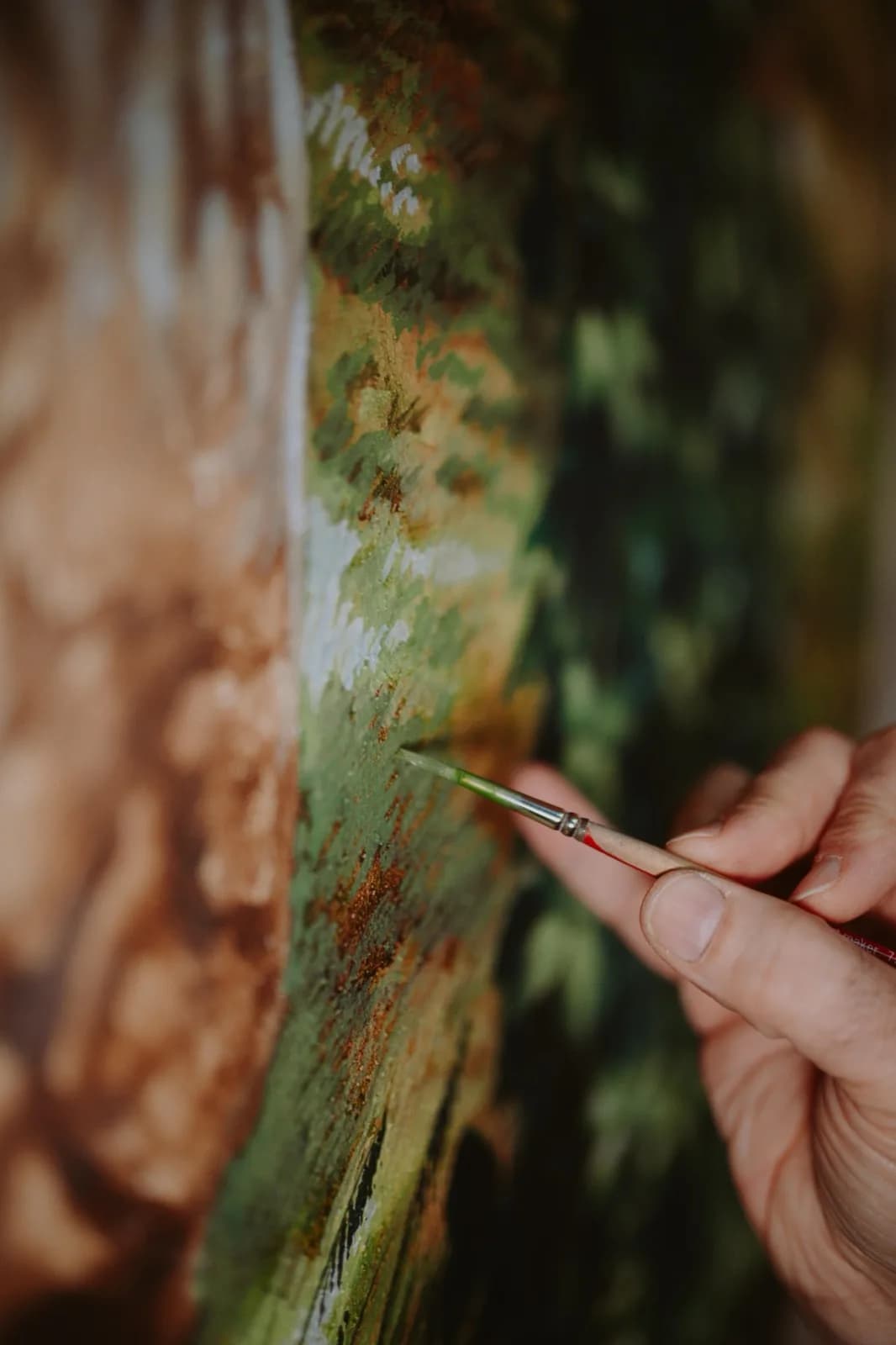 La mano di Lino con il pennello, al lavoro sul dettaglio di un albero del murale